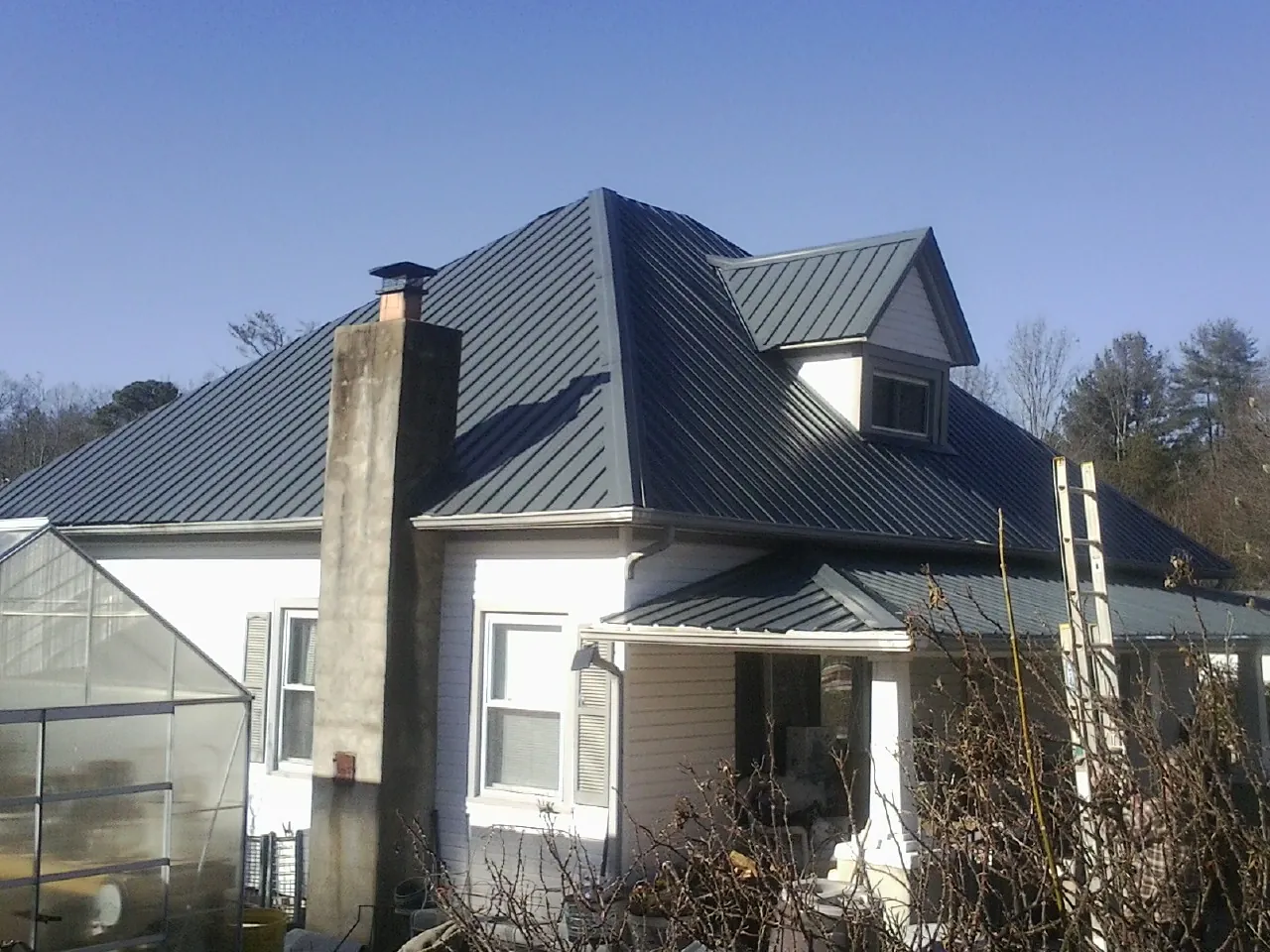 Dark blue standing seam metal roof on a white farmhouse with dormer — Slate & Tile Roof Repair by Roofing Brothers in Bean Station