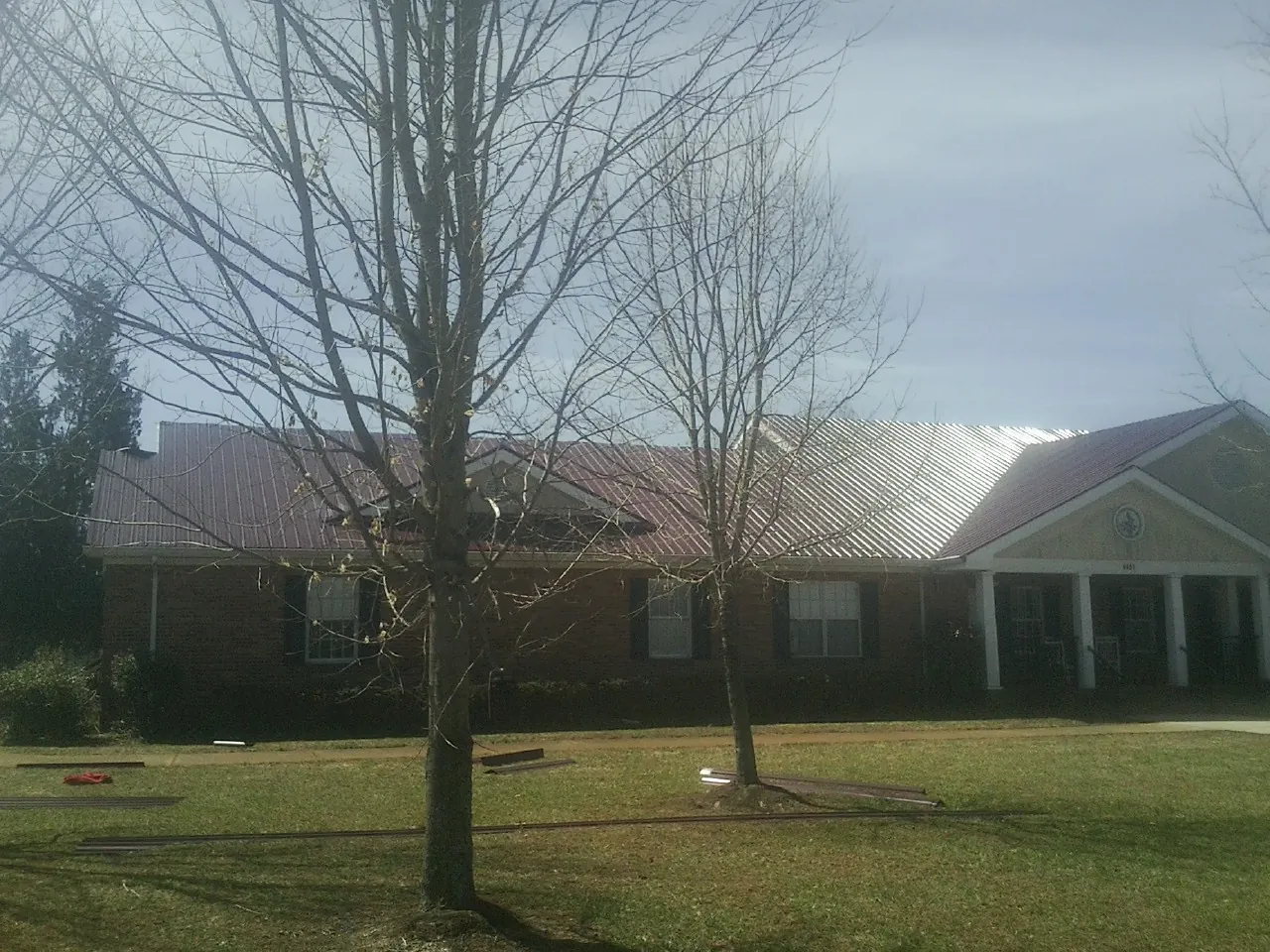 Red metal roof on a brick building seen from the front lawn in Bean Station