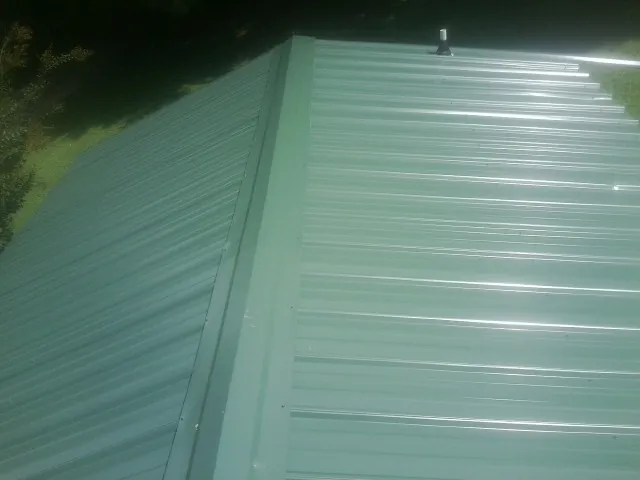 New green metal panels meeting at the ridge of a roof — Flat Roof Repair work by our crew in Bean Station