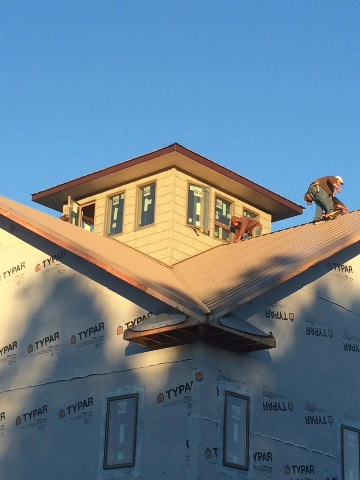 Roofers working around a rooftop cupola on a new metal roof at sunset — Roof Waterproofing in Bean Station by Roofing Brothers